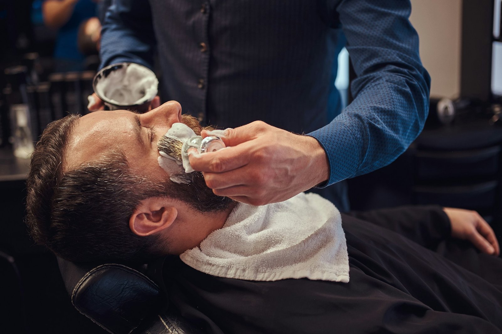 A master hairdresser prepares the face for shaving and smears the face