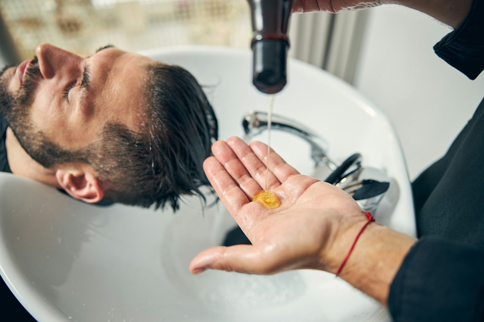 Close up of male hand pouring down shampoo