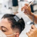 Close up view of a hairdresser colouring the hair of a man on a salon