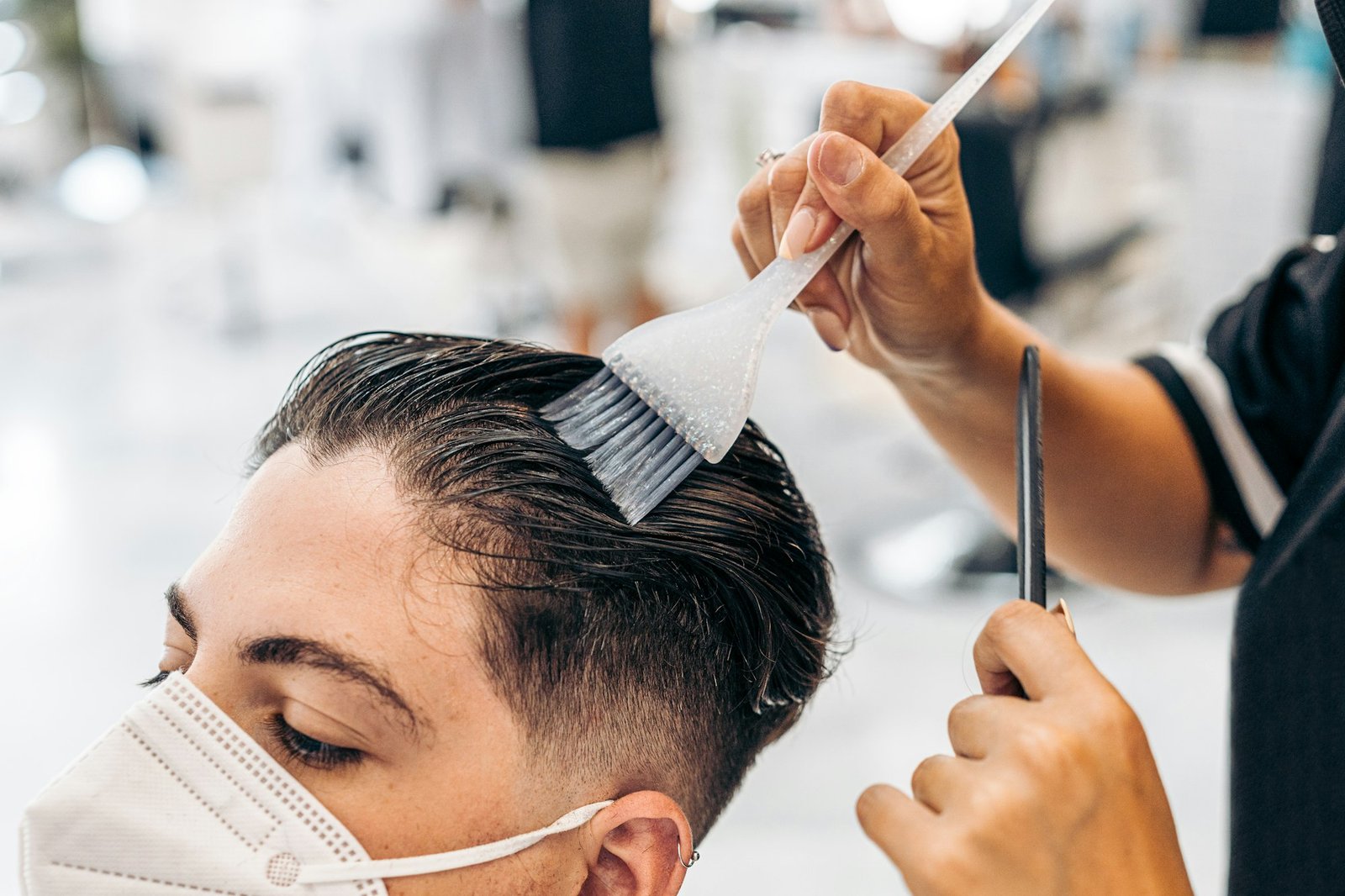 Close up view of a hairdresser colouring the hair of a man on a salon