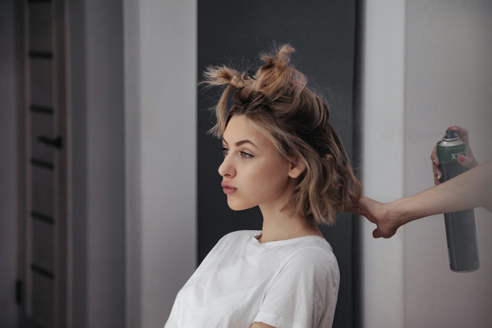 Hairdresser does hairstyle cute pretty young woman in beauty salon