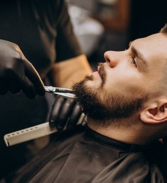 Free Photo _ Handsome man cutting beard at a barber shop salon