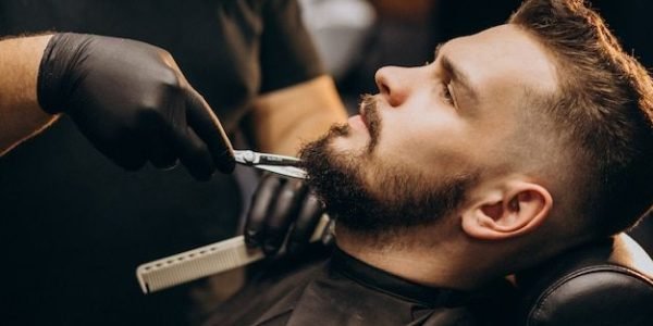 Free Photo _ Handsome man cutting beard at a barber shop salon