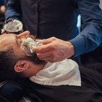 A master hairdresser prepares the face for shaving and smears the face