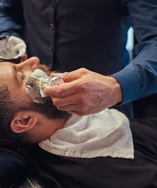 A master hairdresser prepares the face for shaving and smears the face