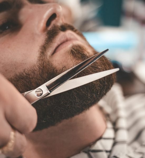 Beard styling and cut. Beard and arm with scissors. Barbershop concept