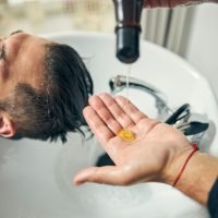 Close up of male hand pouring down shampoo