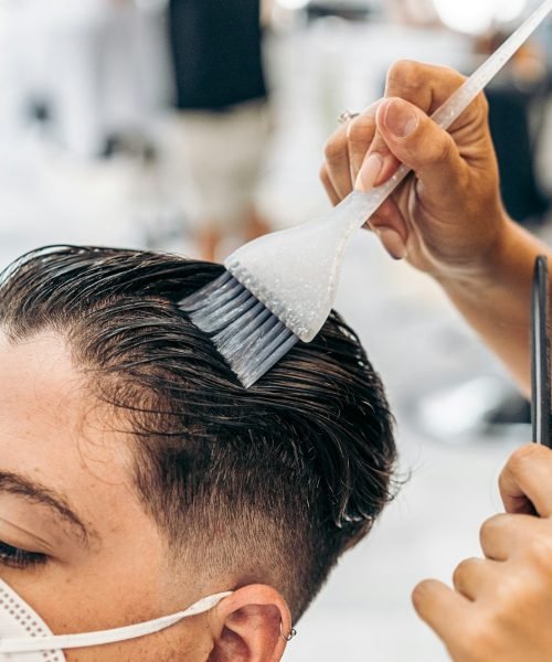 Close up view of a hairdresser colouring the hair of a man on a salon