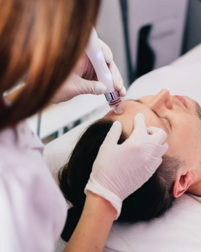 Cosmetologist doing hydrafacial treatment on man face