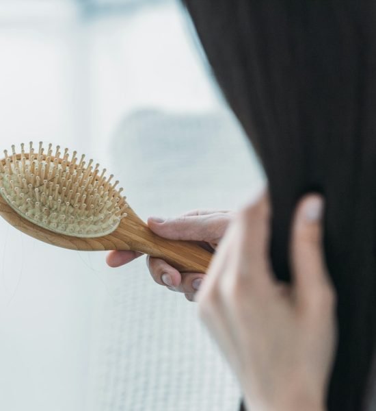 cropped shot of young brunette woman holding hairbrush, hair loss concept