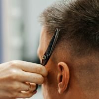 European man is cut by a barber. Men's hair cutting with scissors in the salon