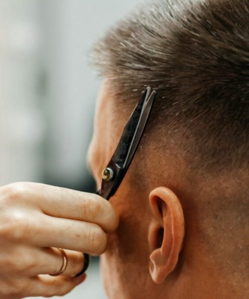 European man is cut by a barber. Men's hair cutting with scissors in the salon