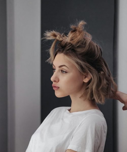 Hairdresser does hairstyle cute pretty young woman in beauty salon
