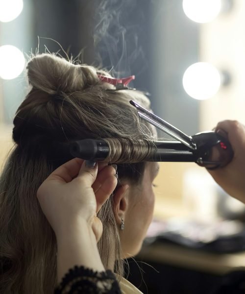 Makeup artist doing hair styling on a curling iron