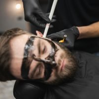 Man in a beauty salon is removing earwax using candles. Male enjoying a spa treatment