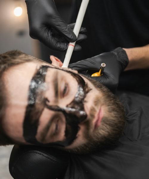 Man in a beauty salon is removing earwax using candles. Male enjoying a spa treatment
