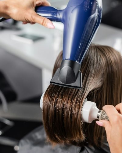 salon blow dry,professional hairdresser with round brush and hair dryer styling hair