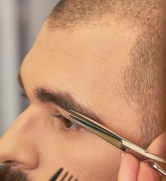 Scissors cutting eyebrow of man